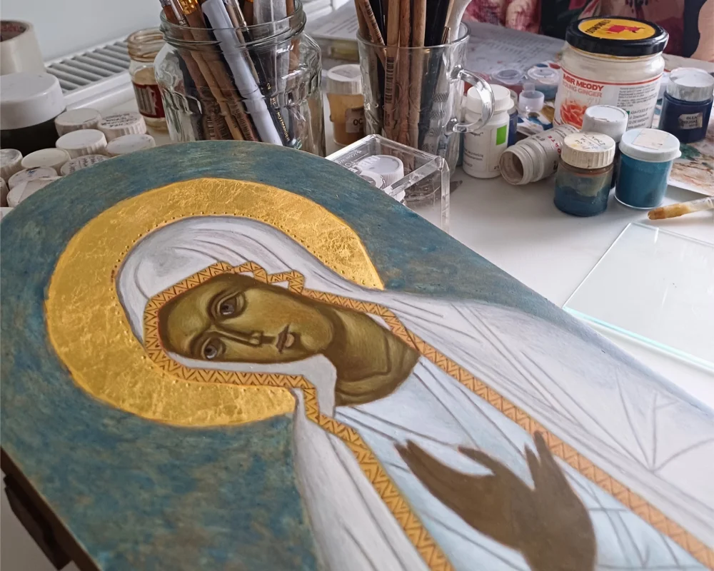 Hand-painted Our Lady of Fatima icon in progress at an iconography studio, featuring a 24K gold leaf halo and traditional egg tempera pigments on a linden wood board.