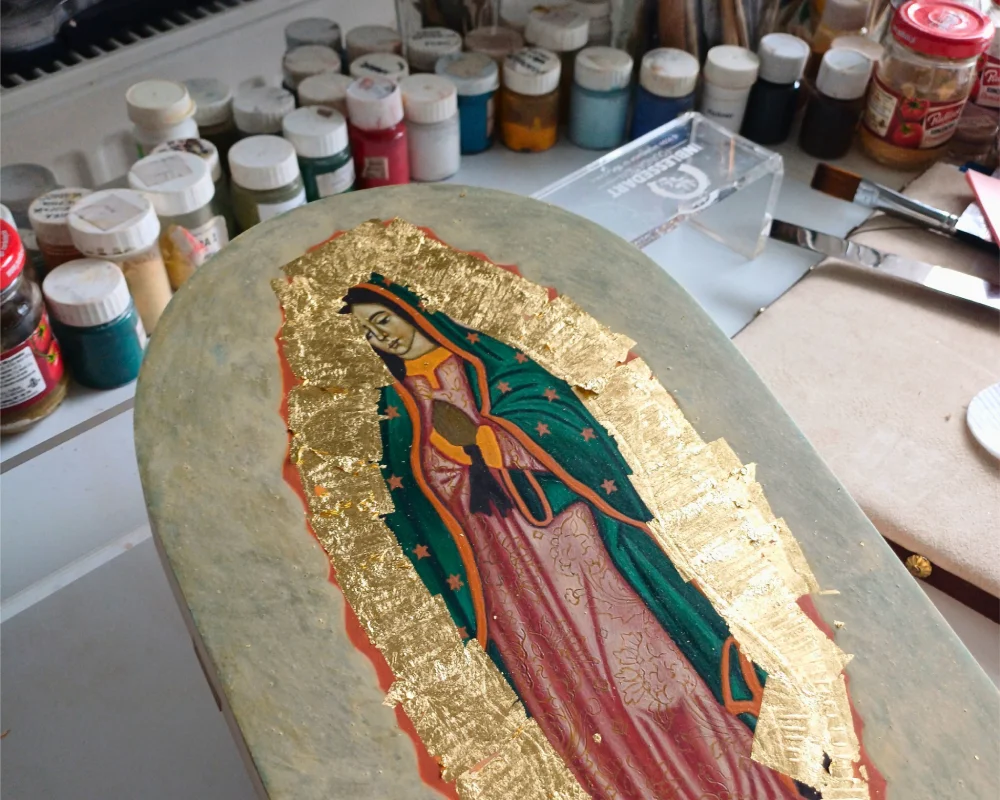 Hand-painted Our Lady of Guadalupe icon showing the assist gilding process with gold leaf